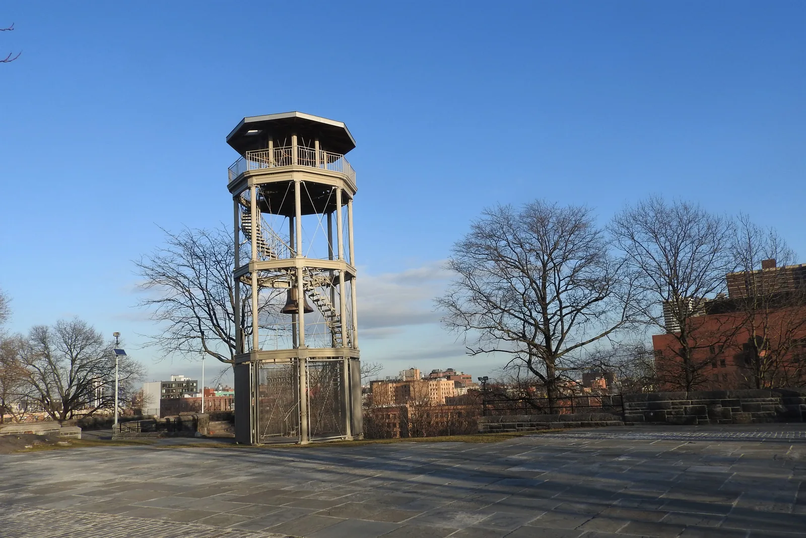 La torre antincendio ottagonale in ghisa nel Marcus Garvey Park, con la sua campana appesa all'interno, su una piazza in pietra sotto un cielo azzurro limpido